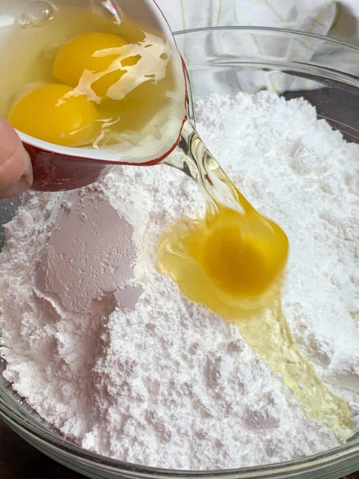 Adding eggs and powdered sugar to a large bowl