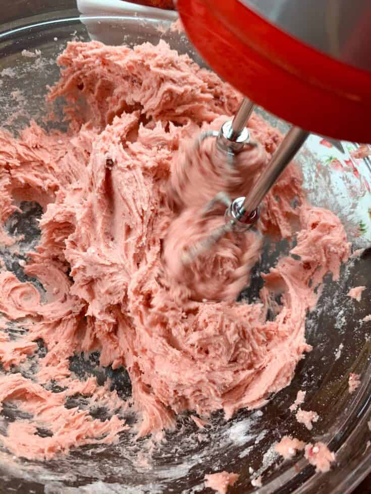 Mixing strawberry cake for chess squares in a glass bowl