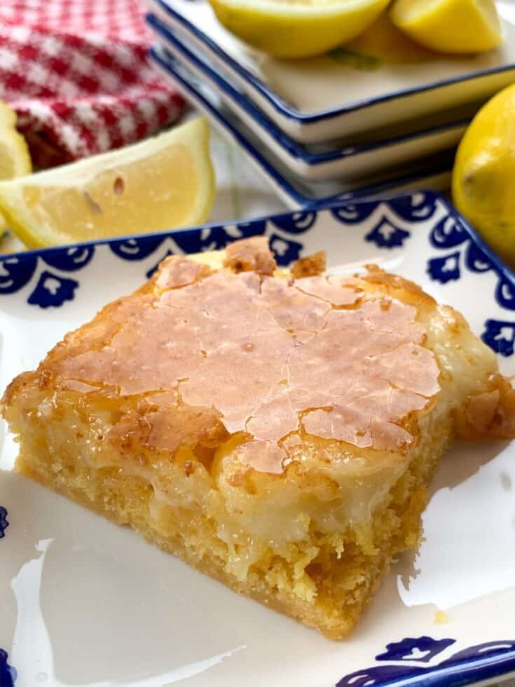 A lemon chess square on a blue and white plate with sliced lemons