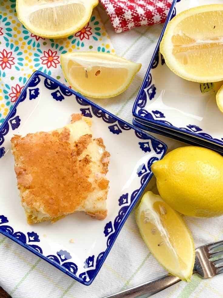 Lemon chess squares on a plate with sliced lemons