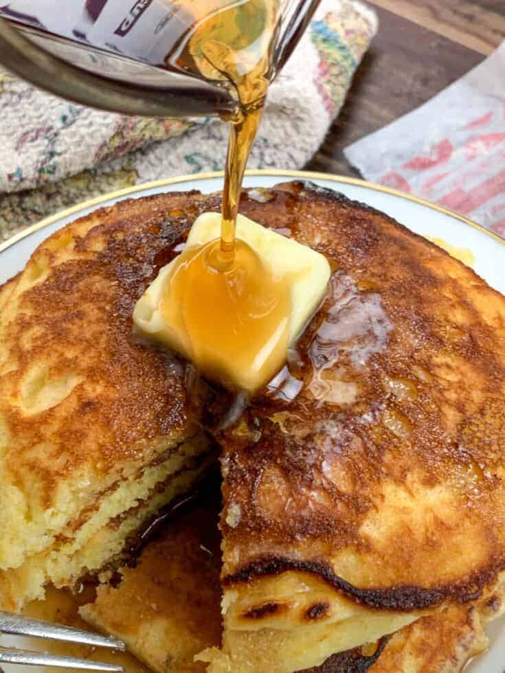 Pouring syrup over butter on Jiffy Cornbread Pancakes