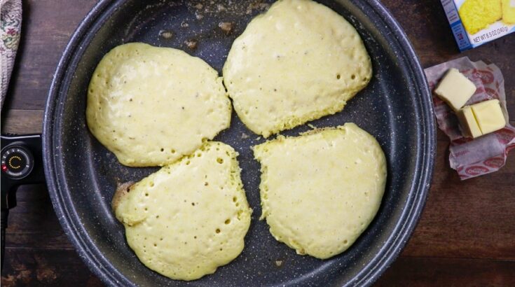 Four pancakes cooking in a skillet