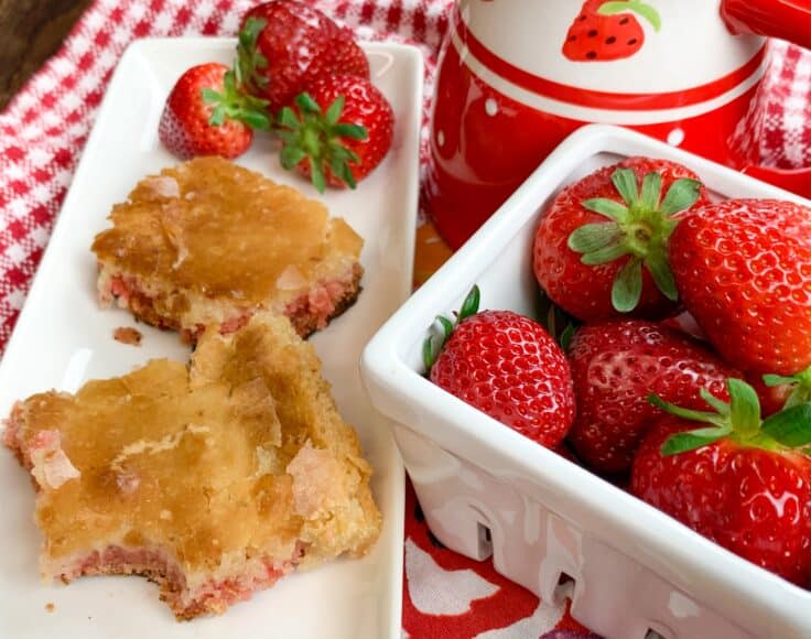 Strawberry chess squares on a white plate with strawberries in a bowl