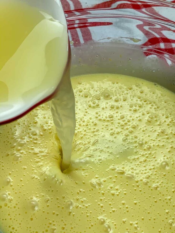 Pouring lime juice into a glass bowl with sweetened condensed milk