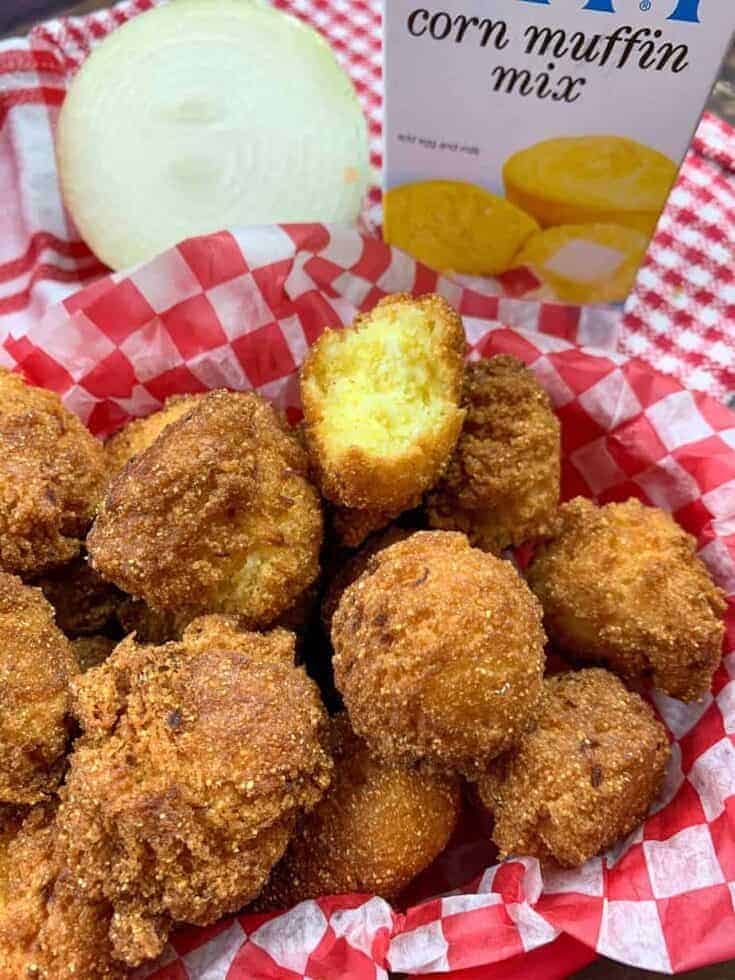 Hush puppies in a basket sitting next to a sweet onion