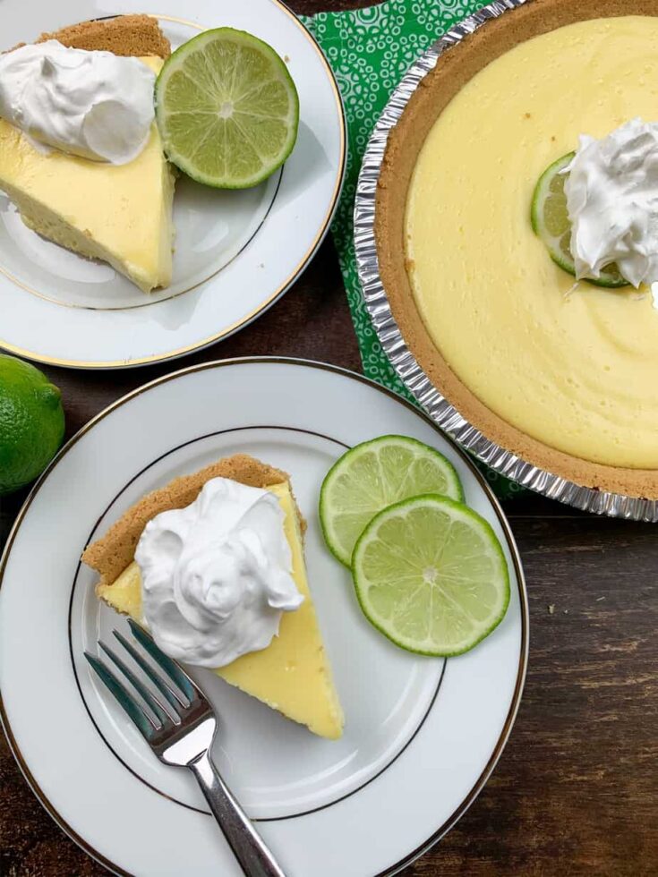 A slice of pie on a plate next to the entire pie. 