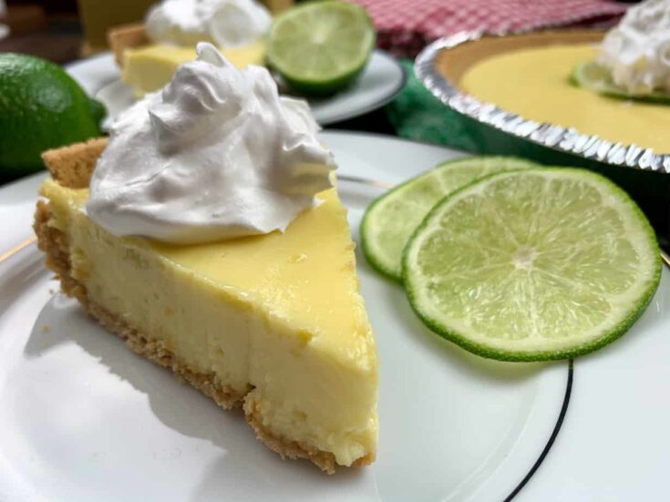 A slice of key lime pie on a plate with whipped topping. 