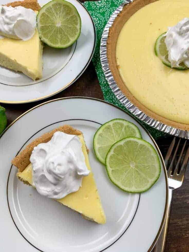 A slice of key lime pie in a plate with limes.