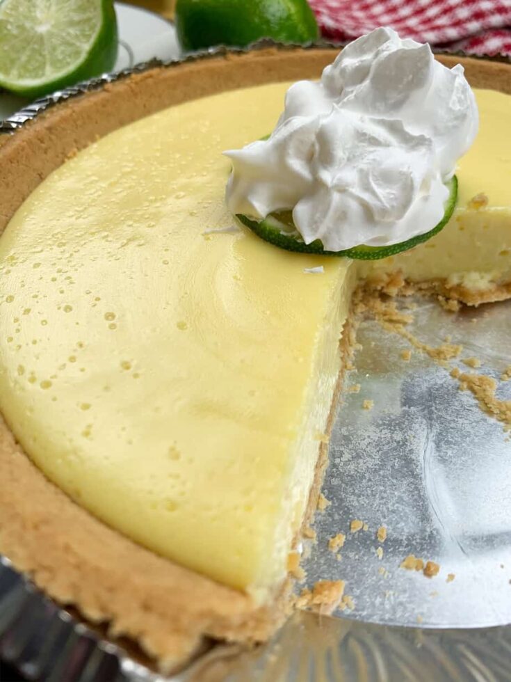 Key lime pie in a pie container with whipped topping.