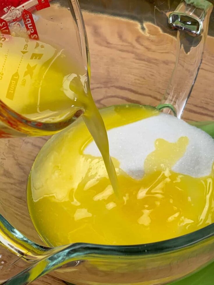 Melted butter being poured into a bowl with sugar.