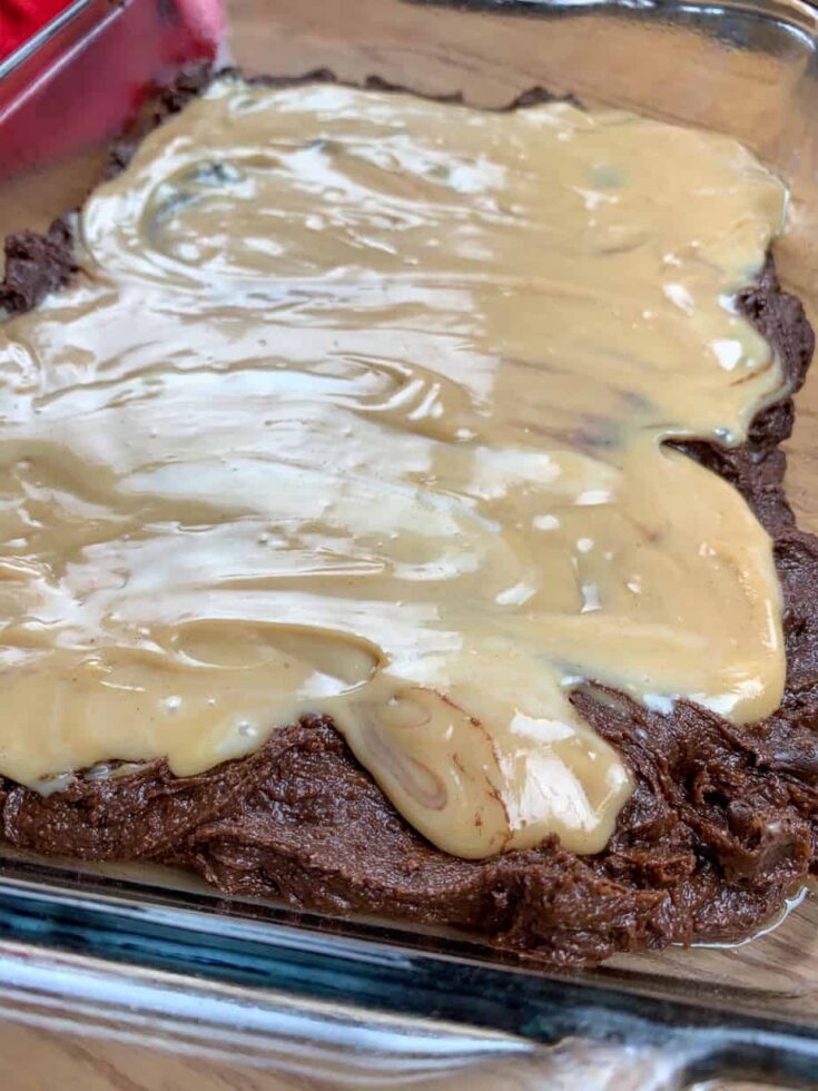 Spreading the sweetened condensed milk and peanut butter over the brownies.